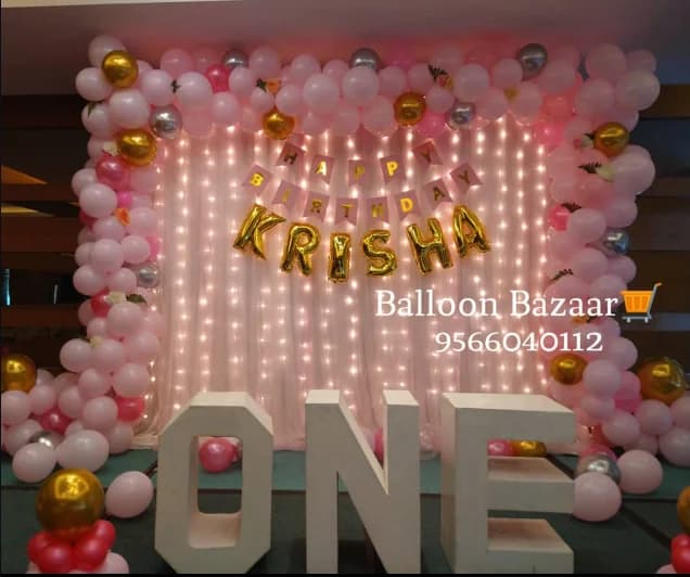 Pink, white and gold balloon backdrop with a personalised happy birthday name display