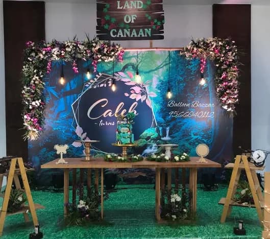 Forest-themed balloon and floral backdrop with a wooden dessert table for a birthday celebration
