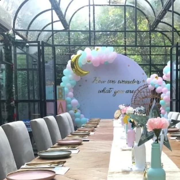 Pastel balloon arch installation in a glasshouse venue with a long celebration table